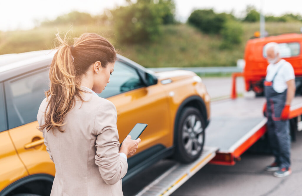 Driver standing beside an orange car at the roadside